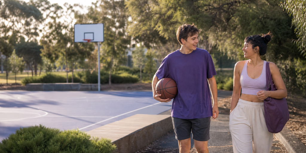 Mentor and young adult walking beside a basketball court
